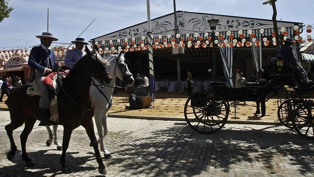 KAKO RANGEL Unos caballistas pasean por el real delante de una caseta y un enganche